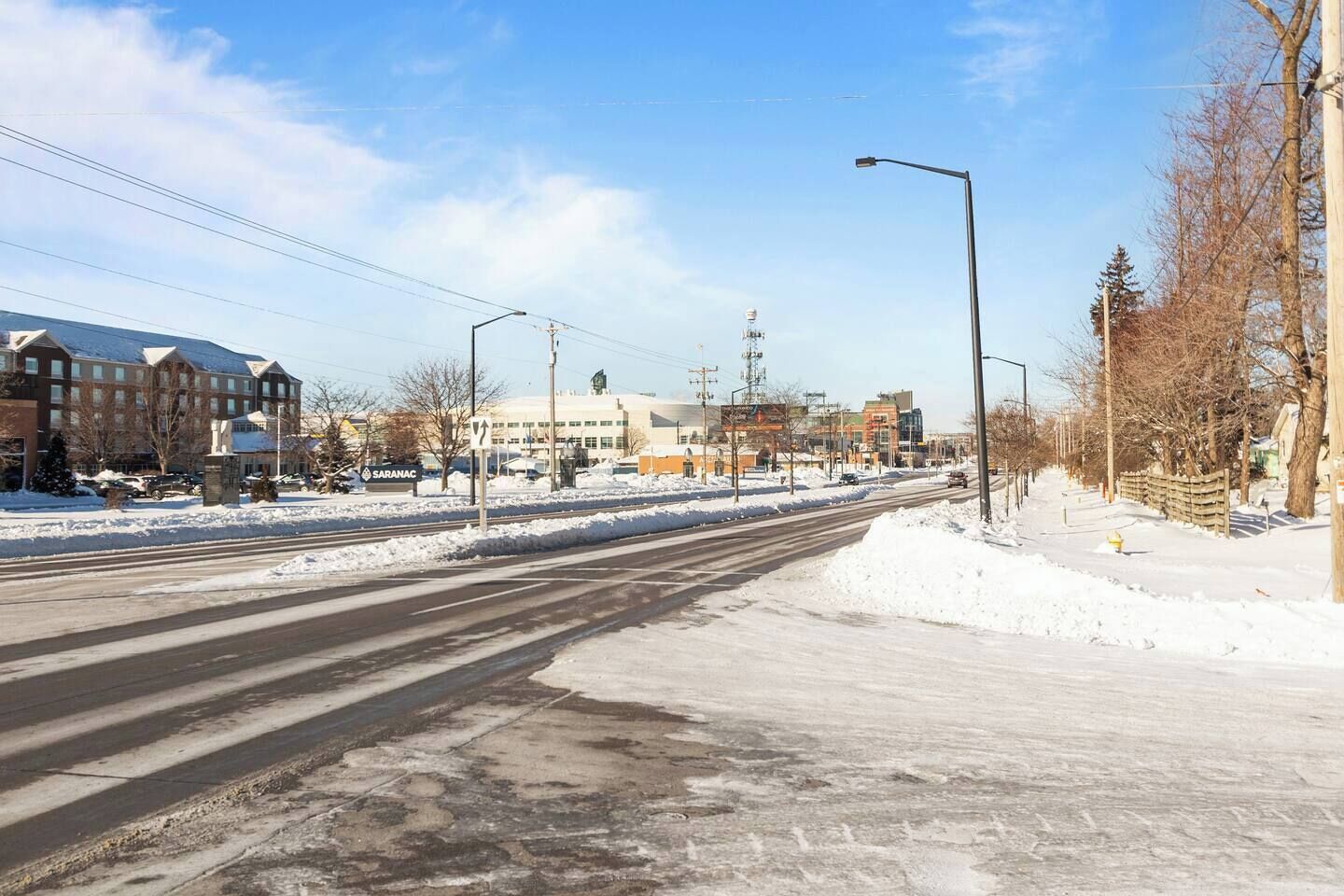 A snow-covered street with buildings, including a hotel with a sign that reads "Saranac."