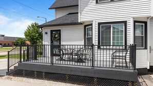A two-story house with a covered porch and a black metal railing.