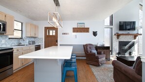 Una cocina moderna con una isla central, armarios de madera y una chimenea de piedra.
