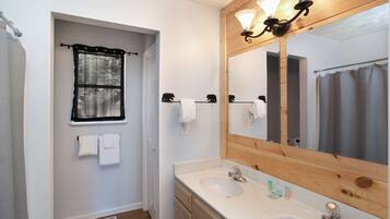 A bathroom with two sinks, a large mirror, and a shower curtain.