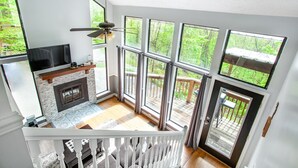 Una habitación con techos altos, chimenea, ventanas amplias y una terraza.