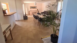A spacious living area with a dining table, chairs, and a potted plant.