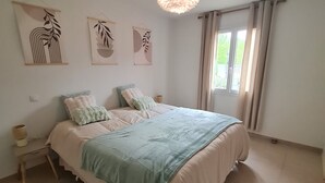 A bedroom with a bed, bedside tables, a hanging light fixture, and artwork on the wall.