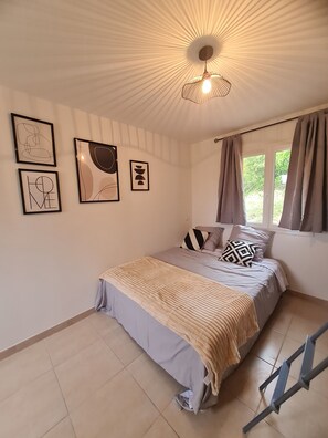 Une chambre à coucher avec un lit, un luminaire au plafond et des œuvres d’art encadrées accrochées au mur.