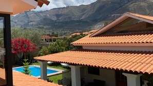 Una vila amb teulada de rajola, piscina i vistes a les muntanyes.