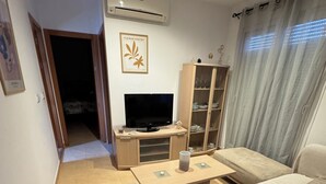 Een moderne woonkamer met een bank, een televisie, een kast en een eettafel.