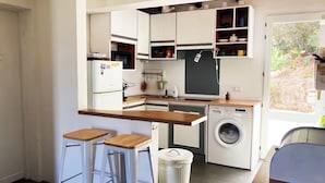 Eine kompakte Küche mit weißen Schränken, einer integrierten Waschmaschine und einer Holz Arbeitsplatte.
