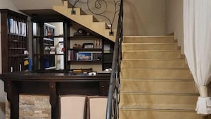 A staircase with a decorative metal railing, a bookshelf, and a dining area with chairs. - Przystan Apartamenty Hotel  (Myslakowice)