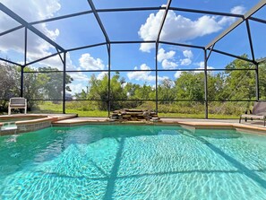 A covered outdoor swimming pool with clear water, surrounded by a metal frame and a view of greenery. - Spacious villa with private pool, hot tub and games room (Davenport)
