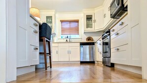 A kitchen with white cabinets, a stainless steel dishwasher, and an oven. - Welcome to your private Ballard retreat! (Seattle)