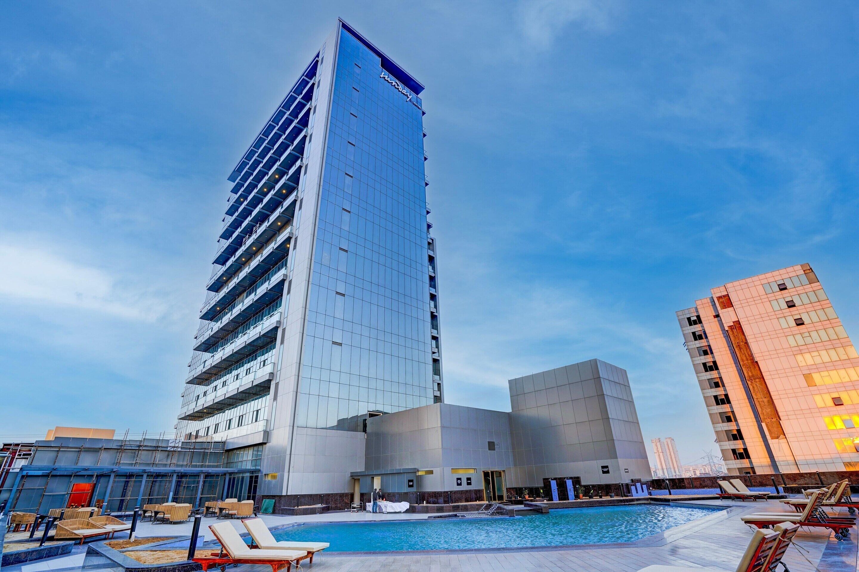 A modern hotel with a rooftop pool area, including lounge chairs and a swimming pool.
