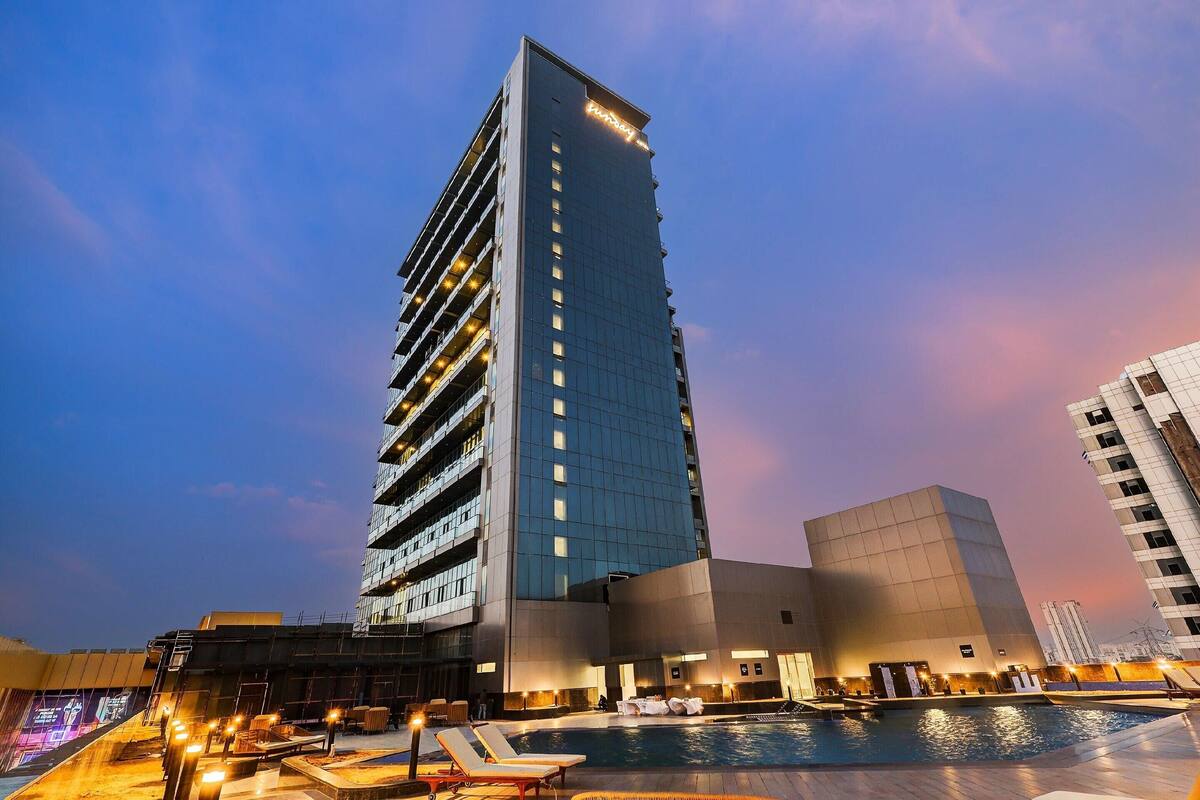 A high-rise hotel with a swimming pool and outdoor seating.