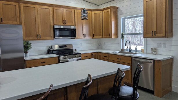 Een moderne keuken met houten kastjes, roestvrijstalen apparatuur en een groot eiland met barkrukken.