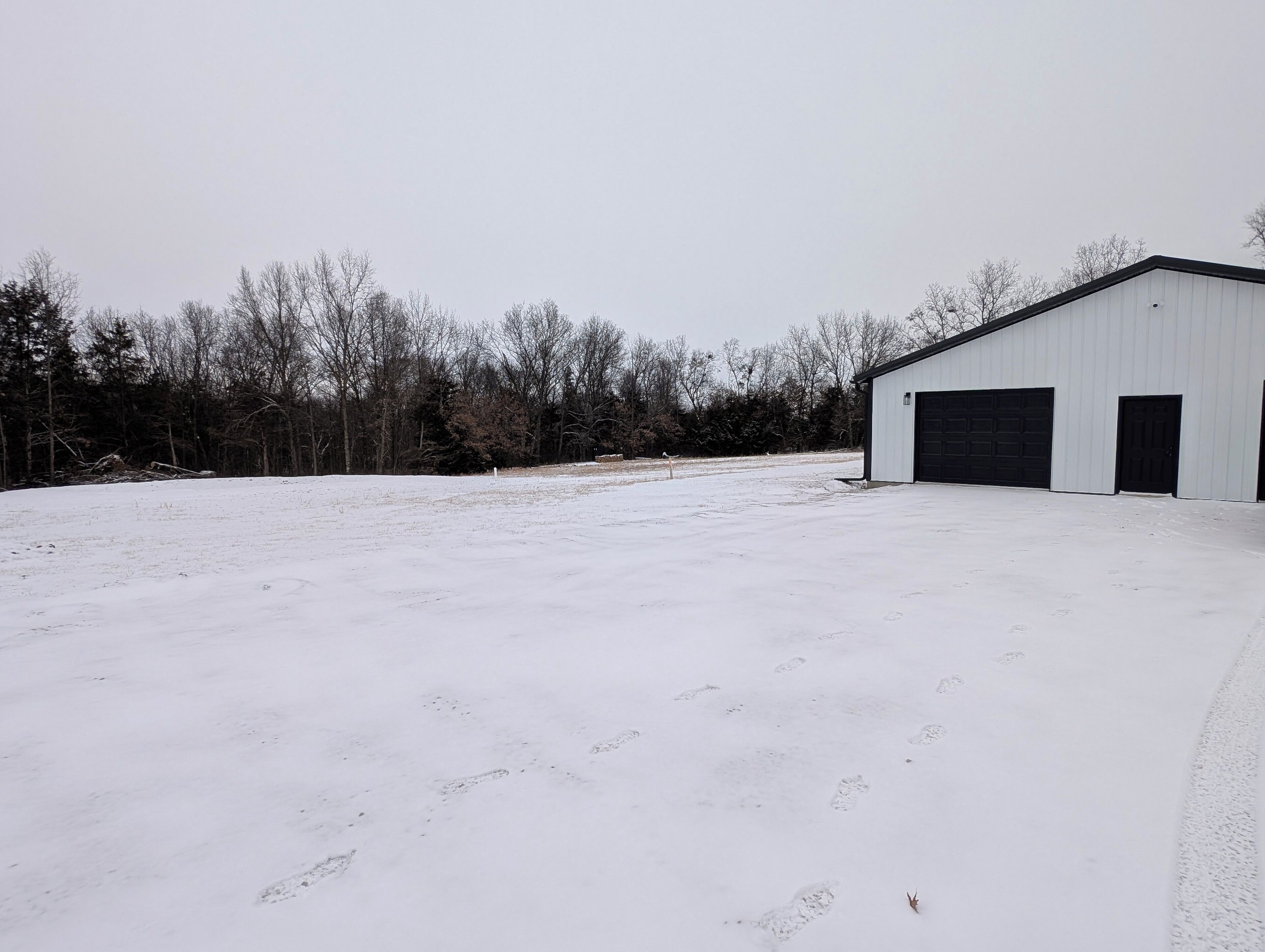 Un parking enneigé avec un bâtiment blanc doté de deux portes de garage.