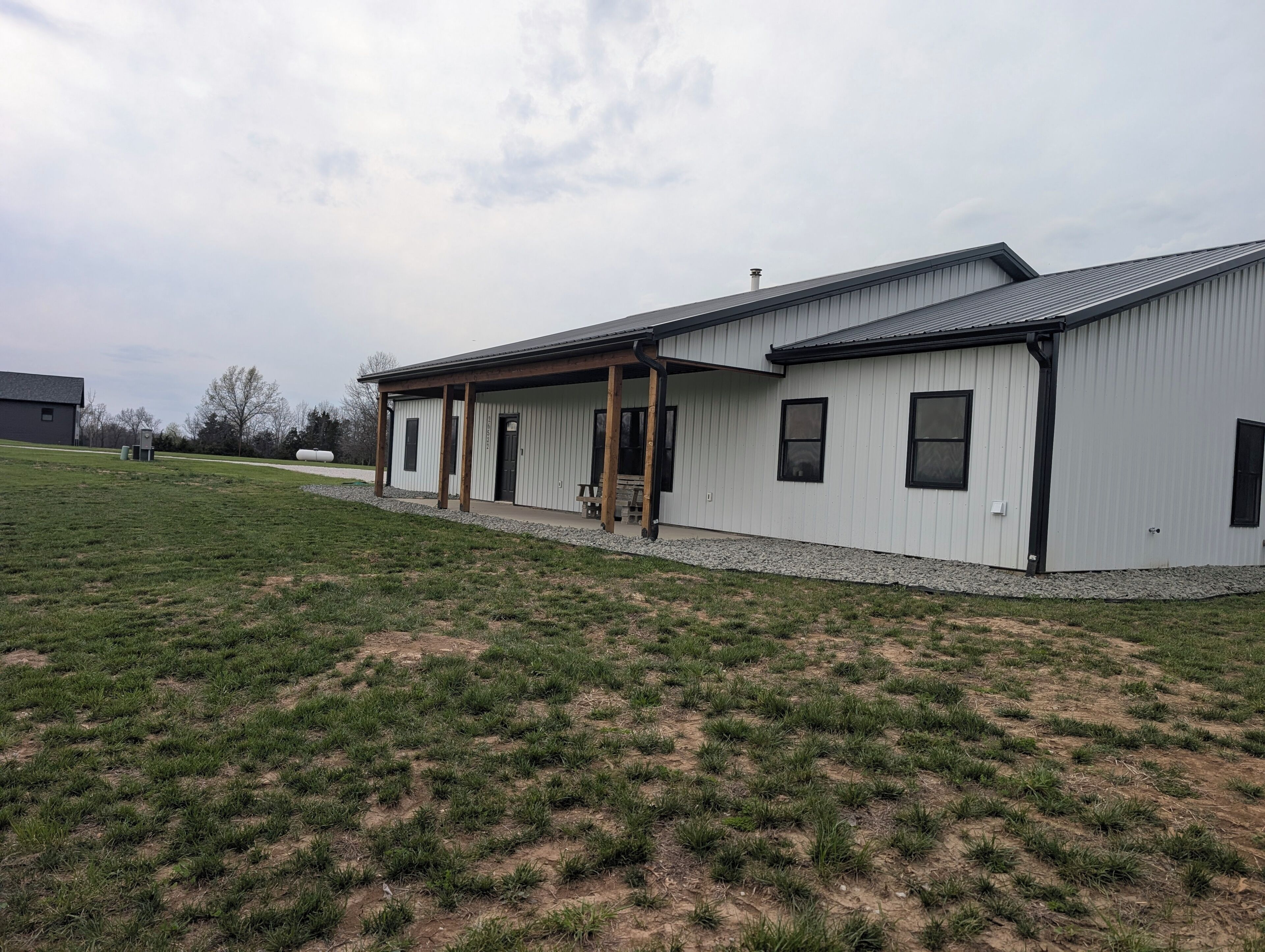 A single-story building with a covered porch, a flat roof, and a gravel driveway.