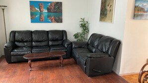A living room with two black leather sofas, a wooden coffee table, and three paintings on the walls. - Family-Friendlyin QuietLaval Neighborhood (Laval)