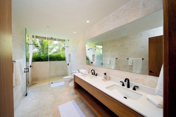 Une salle de bain moderne avec un grand miroir, deux lavabos et un espace douche.