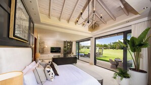 A spacious bedroom with a large bed, a television, and a view of a garden through large windows. - Comfortable, Elegant, Luxury, Pool, Jacuzzi, BBQ (Casa de Campo)