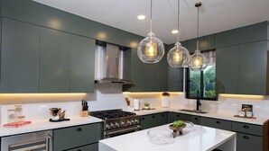A modern kitchen with dark green cabinets, a white countertop, stainless steel appliances, and pendant lighting. - Comfortable, Elegant, Luxury, Pool, Jacuzzi, BBQ (Casa de Campo)