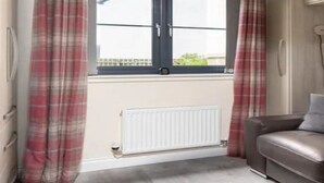 Une pièce avec une fenêtre, un radiateur et un canapé en cuir marron.