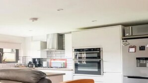Une cuisine moderne équipée d’appareils électroménagers en acier inoxydable, notamment un réfrigérateur, un four et un four à micro-ondes.