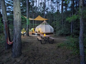 A tent with a canopy, surrounded by trees, and a picnic table with a lantern. - Rustic Glamping with Goats in Forest Near Houston (Cleveland)