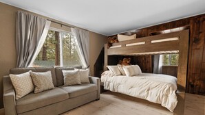 Een slaapkamer met een stapelbed, een slaapbank met decoratieve kussens en een raam met gordijnen.