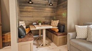 Een gezellige zithoek met een houten wand, een tafel en twee wandlampen.