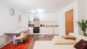 A compact living space with a kitchenette, dining area, and a sofa. - Apartmentsleeps4-citystay-view Over River Irwell (Salford)