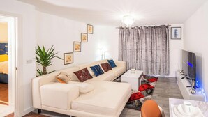 A modern living room with a beige sofa, a flat-screen TV, and a red and black rug. - Apartmentsleeps4-citystay-view Over River Irwell (Salford)
