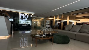 Un salón moderno con fachada de vidrio, una mesa de centro redonda y un sillón de felpa verde.