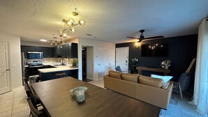 A modern kitchen with dark cabinets, a wooden dining table, and a ceiling fan. - The Retreat at Sunset Harbor (Navarre)