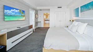 A modern bedroom with a large bed, a TV mounted on the wall, and a walk-in closet.