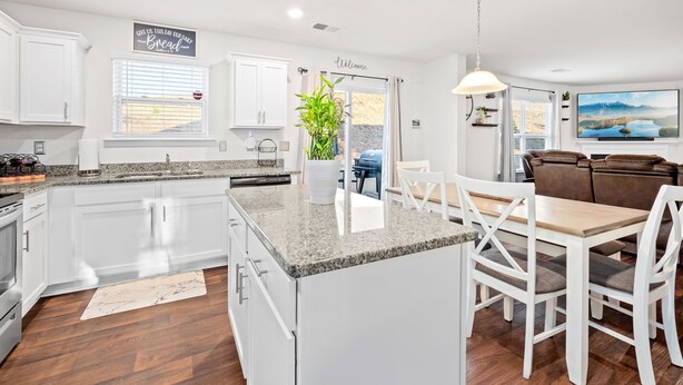 A modern kitchen with white cabinets, granite countertops, and a central island. There is a dining area with a wooden table and white chairs. - Clemson University (6 min) - 1kMbps Internet - Easy Check In - Office Space (Pendleton)