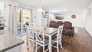 A modern kitchen with white cabinetry, a granite countertop, and a dining area with white chairs and a wooden table. - Clemson University (6 min) - 1kMbps Internet - Easy Check In - Office Space (Pendleton)