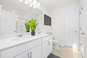 A modern bathroom with a white vanity, a large mirror, and a potted plant. - Clemson University (6 min) - 1kMbps Internet - Easy Check In - Office Space (Pendleton)
