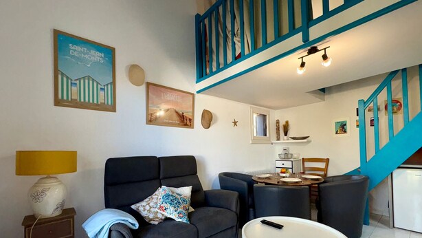Una sala de estar con un sofá, una mesita y una escalera con barandillas azules.