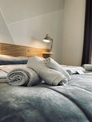 A neatly made bed with rolled towels and a bedside lamp. - B&B Tre Ponti (Taranto)