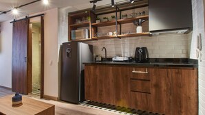 A modern kitchen with wooden cabinets, a black refrigerator, and a countertop with a coffee maker.