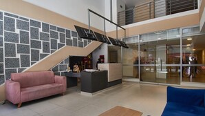 A lobby with a reception desk, a pink sofa, a blue sofa, and a wooden coffee table.