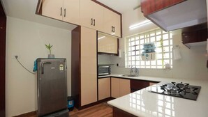 Cocina compacta con refrigerador, estufa y ventana con dispensador de agua.