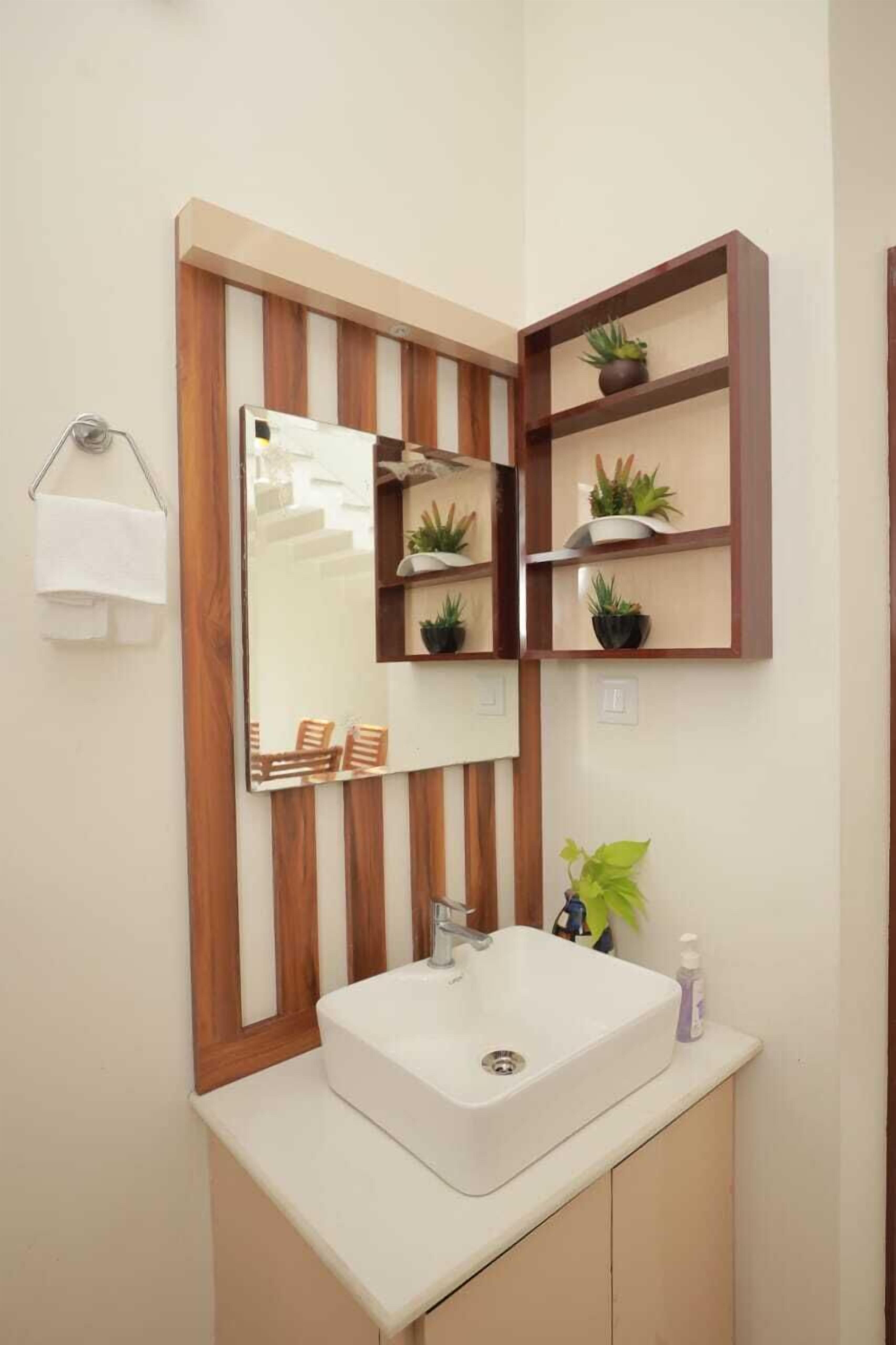 A bathroom with a white sink, wooden shelves with plants, a mirror, and a towel rack.
