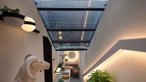 Ein modernes Interieur mit Oberlichter, einer Skulptur und einer Topfpflanze.