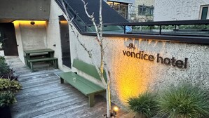 Eine Holzterrasse führt zu einem Gebäude, an dem das Schild "Vondice Hotel" zu sehen ist.