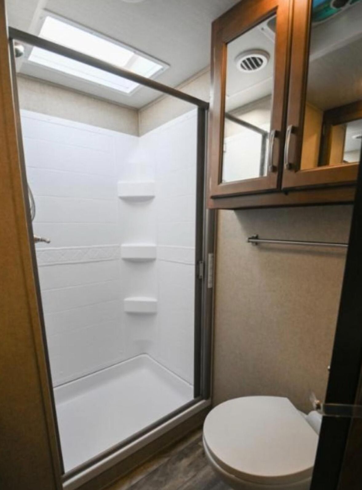 Un baño pequeño con ducha, inodoro y un mueble auxiliar.