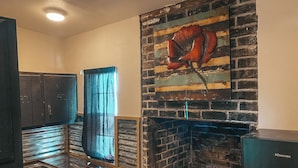 Una cocina con pared de ladrillo, un lavamanos, armarios y un refrigerador.