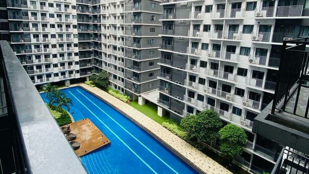 Un edificio residencial alto con varios balcones y una piscina.