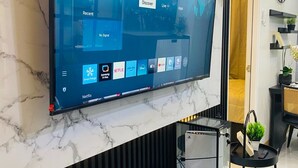 Una sala de estar moderna con un televisor de pantalla plana grande montado en una pared de mármol, un mueble negro de entretenimiento debajo y una decoración de estilo minimalista.