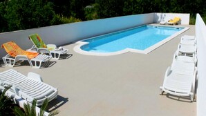 Una piscina con sillones de descanso y una pared blanca.