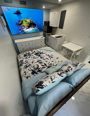 Un dormitorio con cama, televisor, escritorio y silla.